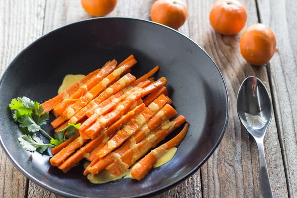 Tequila Carrots in black bowl, drizzled with Curry Tahini Sauce