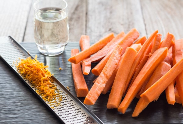 carrot sticks, orange zest in grater and a shot of tequila 