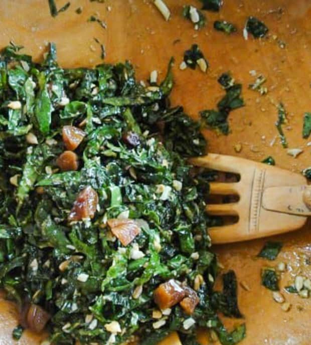 closeup of kale salad with apricots in wooden bowl with salad tong
