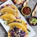 Purple Potato and Bean Tacos arrange on white plate with condiments on the side