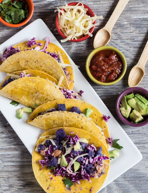 Purple Potato and Bean Tacos  arrange on white plate with condiments on the side