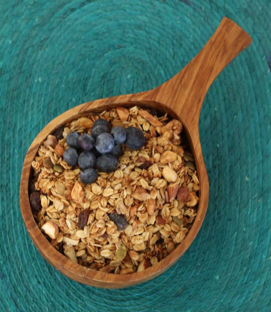 granola in wooden bowl with a few blueberries