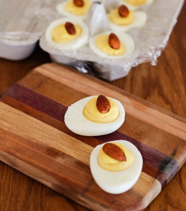 Tamari Deviled Eggs in carton and tow on wooden board