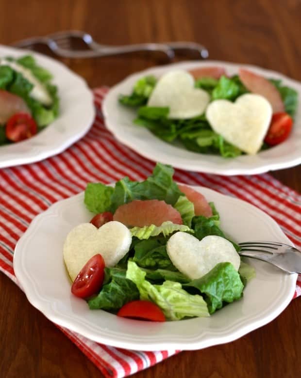 Jicama Heart Salad with Cumin Lime Dressing, pink grapefruit sections and grape tomatoes on white plates with red checked napkin