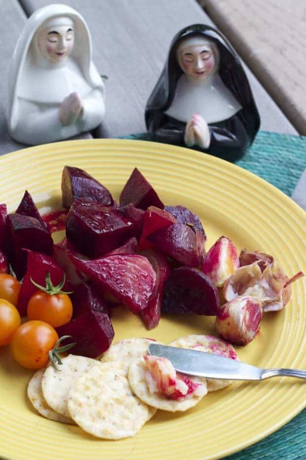 Grill Roasted Beets and Garlic on yellow plate with crackers and a butter knife, with nun salt and pepper shakers