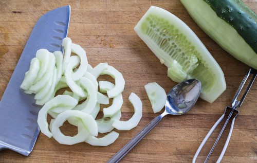 Peeling, scraping seeds, and slicing cucumbers.