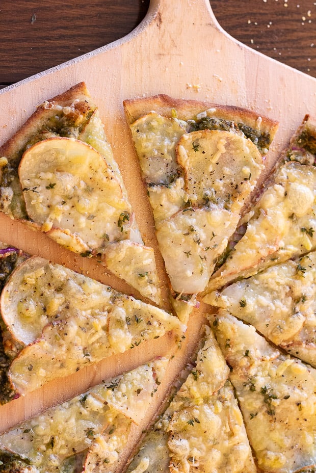 baked Potato Pesto Pizza on wooden board cut in wedges