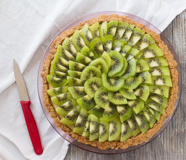Kiwi Lime Avocado Pie with kiwis arranged on top and red handled knife