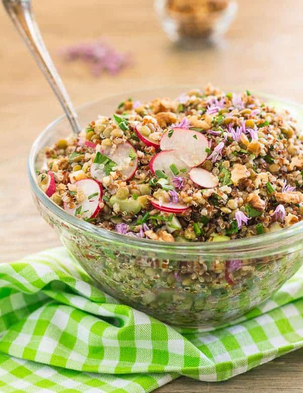 French Green Lentil and Quinoa Salad in glass bowl with spoon on green checked napkin