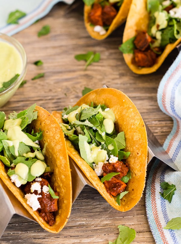 closeup of tacos in holder and bowl of with avocado crema