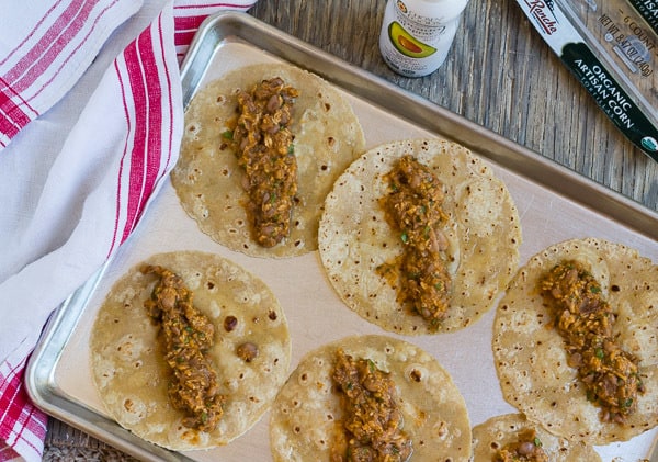tortillas with filling on a baking sheet before rolling into flautas