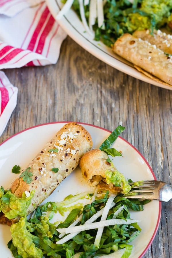taquito flautas on plates with green shredded lettuce and jicama