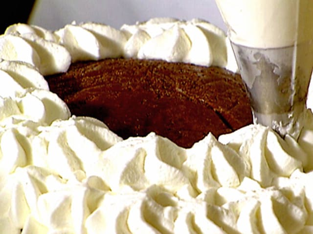Piping whipped cream on chocolate snowball cake