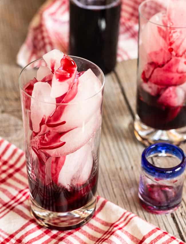 hibiscus syrup poured in glass over ice for hibiscus sparkling soda spritzers