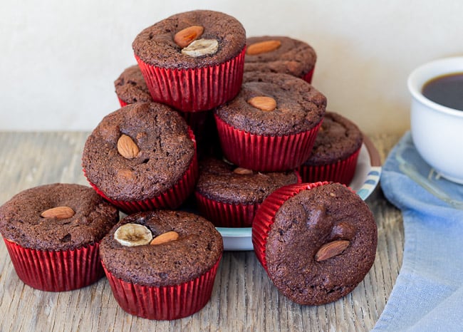 chocolate banana almond muffins on plate with cup of coffee off to the side