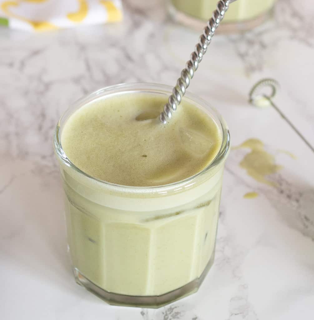 French jelly jar with iced matcha oat milk latte with spiral spoon in cup