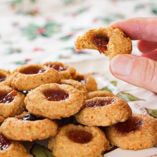 cornmeal thumprint cookies with finger holding one cookie with a bite