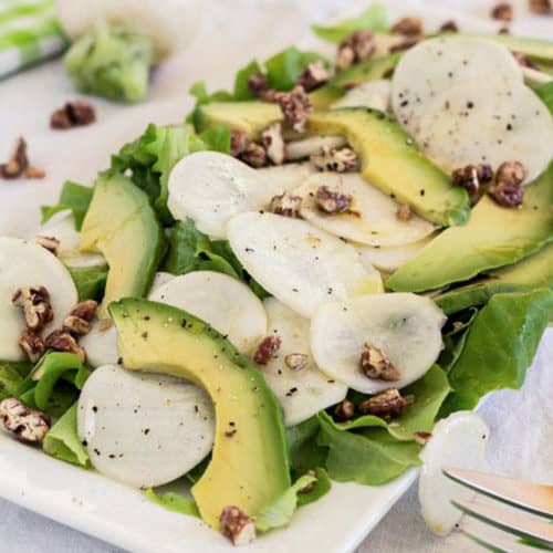 white turnips on white plate with avocado and candied pecans