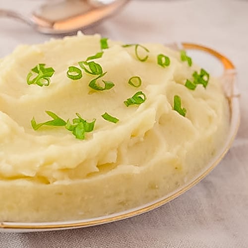 mashed potatoes with green onion garnish in oval serving dish